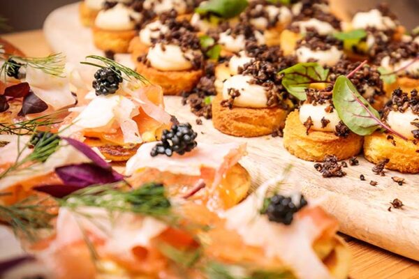 prachtig gedresseerde hapjes gepresenteerd op een houten plankje voor een catering event van KonseptS